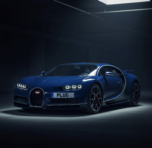 Blue Bugatti car with 'PLUG' license plate in a dark setting