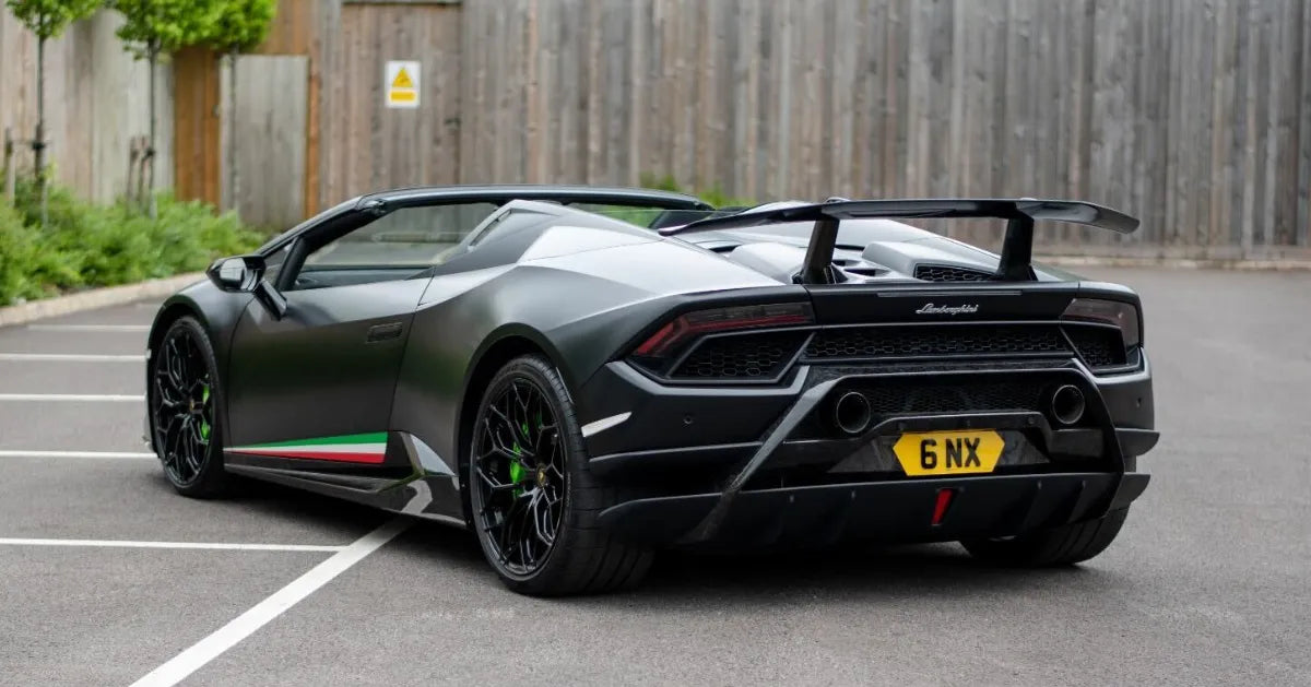 Black Lamborghini Huracan with a visible license plate on a road.