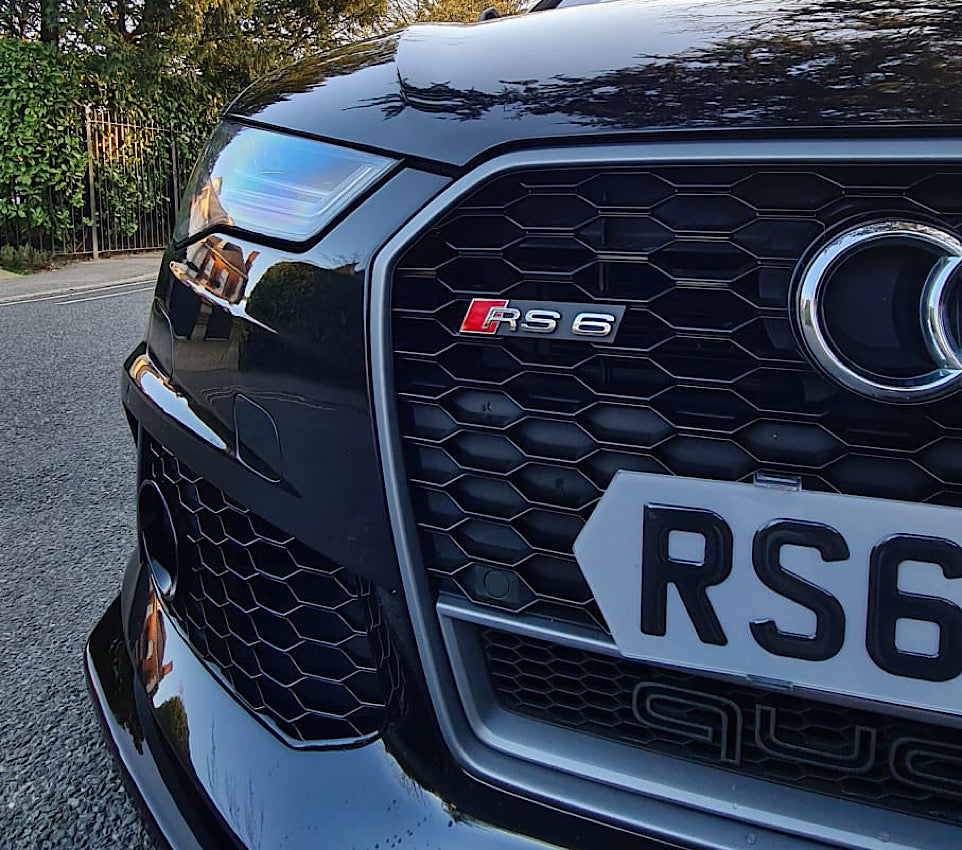 Close-up of an Audi RS6 car grille with visible branding.