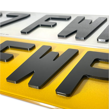 Close-up of a license plate with black text on a white and yellow background