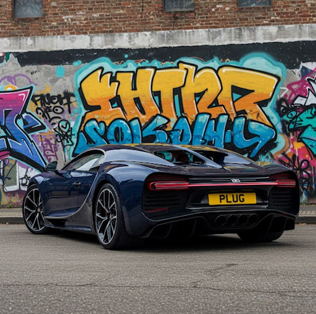 Black sports car with a yellow license plate in front of graffiti-covered walls.